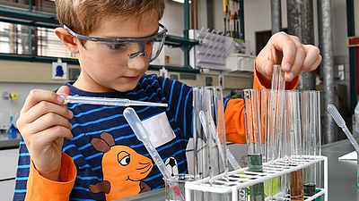 Kleiner Junge steht im Chemielabor der Hochschule Esslingen