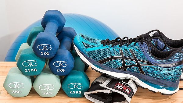 Sports shoes, dumbbells and a gymnastic ball are in the foreground