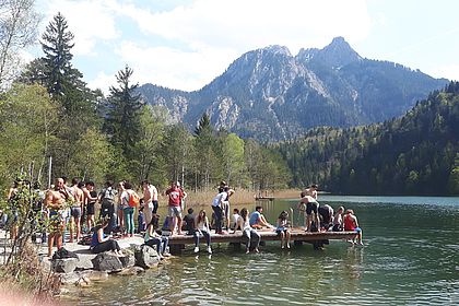 Studierende stehen auf einem Steg am See