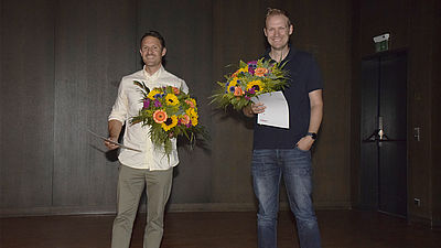 Tobias Heer und Philipp Schreiber stehen mit der Urkunde für den Lehrpreis auf der Bühne.