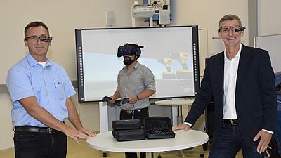 Zwei Männer mit Datenbrille und ein dritter Mann mit Virtual-Reality Kamera im Hintergrund