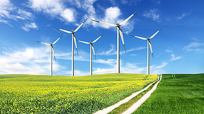 Auf einem grünem Feld sind Windkraftanlagen zu sehen.