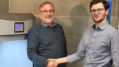 Ein älterer und ein jüngerer Mann geben sich die Hand in einem Labor der Hochschule Esslingen