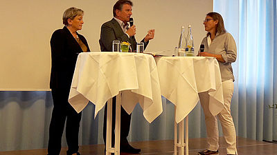 Kultusministerin Dr. Susanne Eisenmann und Sozialminister Manne Lucha gemeinsam mit Professorin Prof. Dr. Elsbernd diskutierend auf der Bühe  
