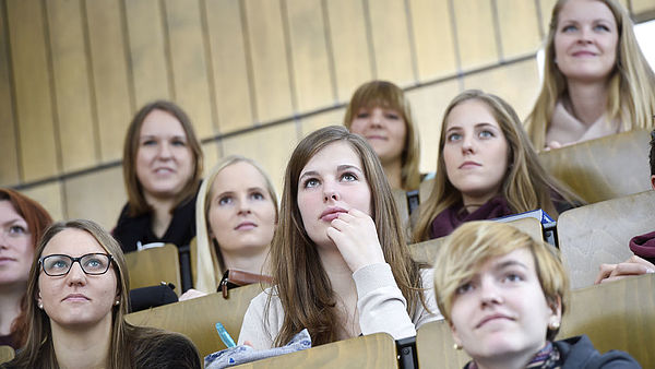 several students in the lecture hall from the front while listening to a lecture