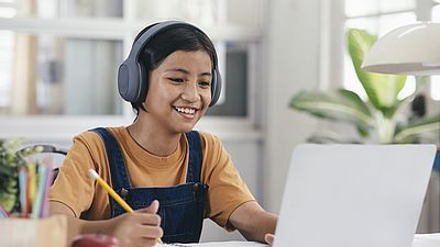 Schülerin mit Kopfhörer sitzt vor einem Laptop