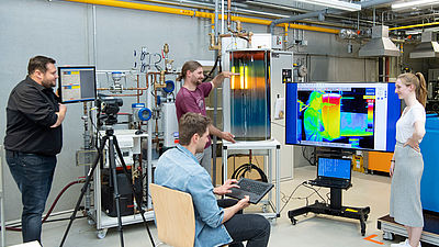 Vier Studierende im Labor für Gebäude-, Energie- und Umwelttechnik bei einem Versuch.