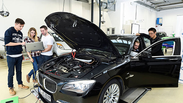 Fünf Studenten analysieren einen schwarzen 7er BMW.