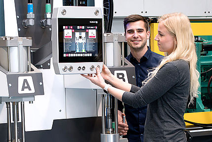 Two students operate machine in mechanical engineering lab