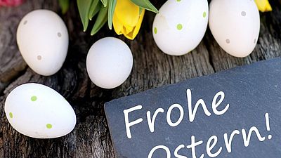 Ostereier und Tulpenstrauß mit Schild Frohe Ostern