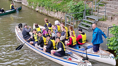 Zwei Kanus auf einem Fluss mit jungen Leuten darin. 