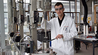 Ein Mann steht in einem Labor neben einer Maschine.