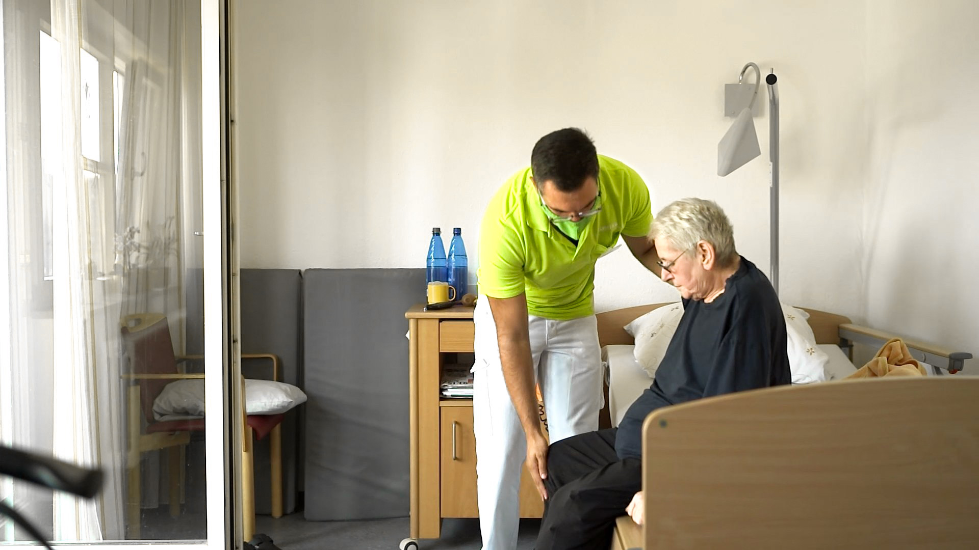 Pfleger assistiert einem älteren Menschen beim Aufstehen