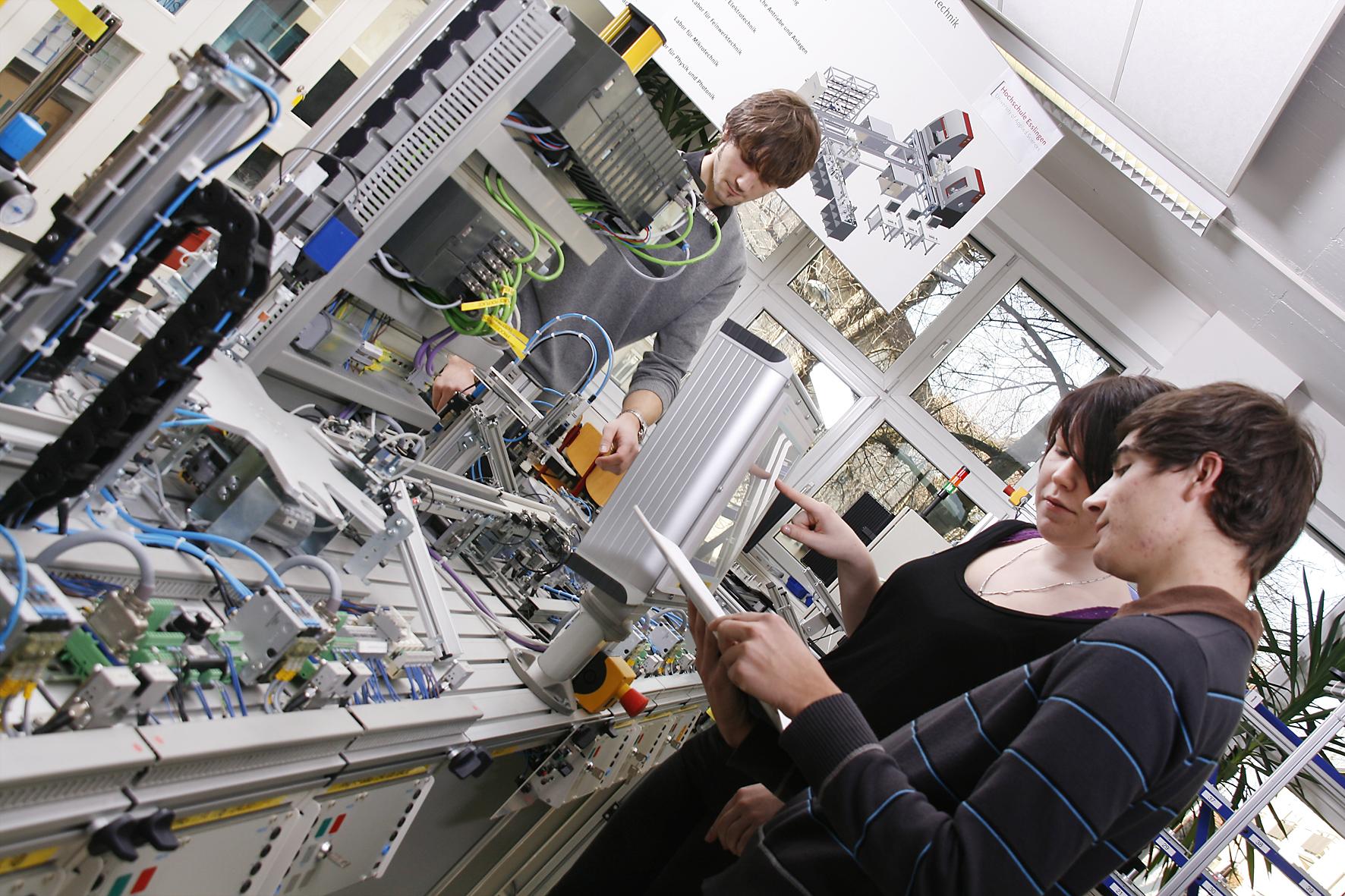 Drei Studenten im Labor vor verschiedenen Geräten.