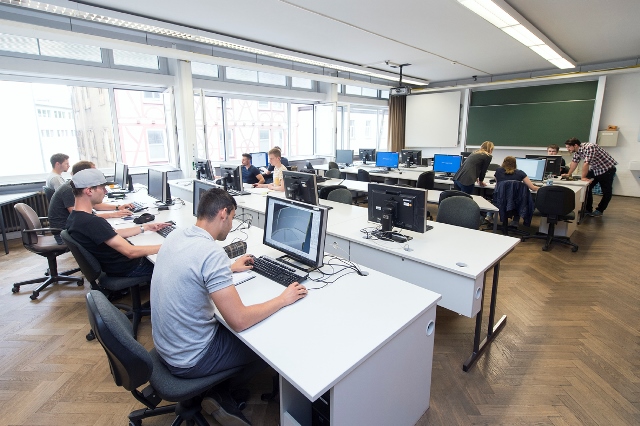 Studierende sitzen an Computern im Hörsaal